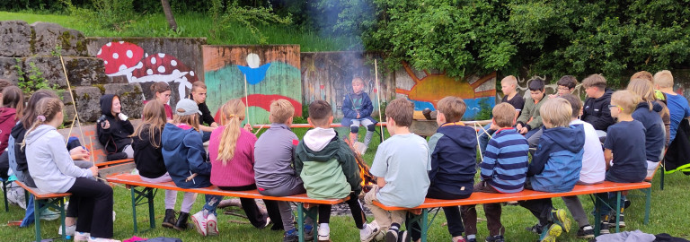 Kinder sitzen um Lagerfeuer