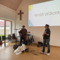 Zwei Gitarrenspieler vor an die Wand projizierter Leinwand