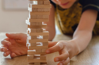 Kind baut mit Jengasteinen einen Turm