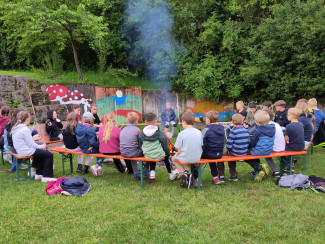 Kinder sitzen um Lagerfeuer